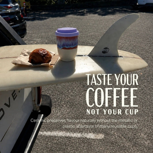 Ceramic coffee cup with a donut on a surfboard with promotional text.