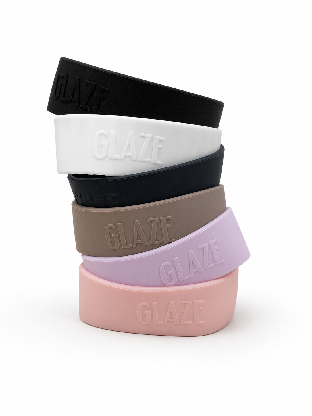 Five silicone coffee cup bands in black, white, dark navy, taupe, lavender, and light pink, stacked vertically on a white background. Each band features the brand name 'GLAZE' embossed on the front.