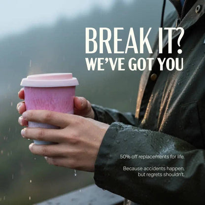 A person in a wet black jacket holds a pink reusable coffee cup outdoors in the rain, with large white text reading “BREAK IT? WE’VE GOT YOU” and smaller promotional text on a moody blurred background.