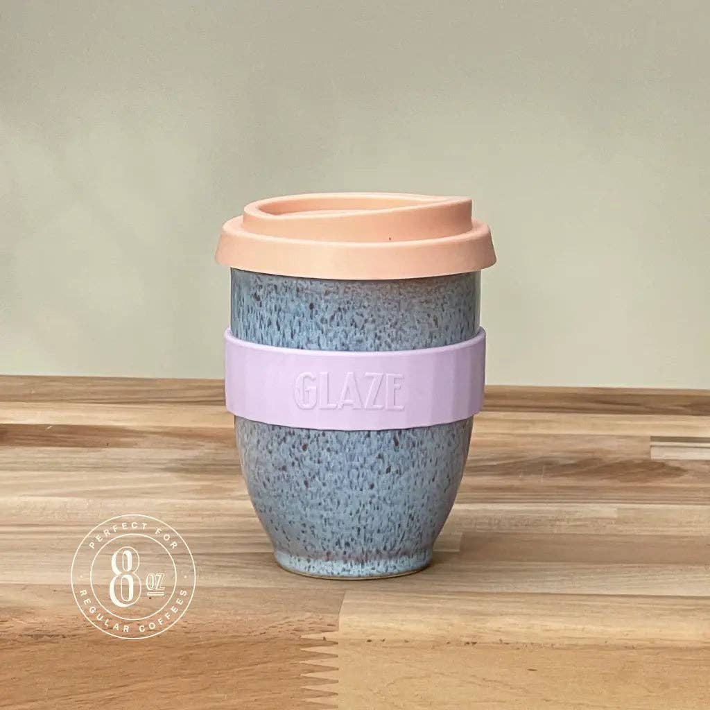 Reusable cup with a pink lid and purple band on a wooden surface