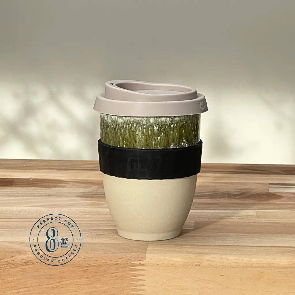 Reusable coffee cup with a black sleeve on a wooden surface