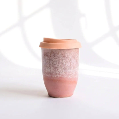 Ceramic tumbler with a textured surface and pinkish-brown color on a white background