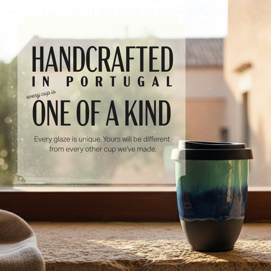 A ceramic travel tumbler with a black lid sits on a stone surface in front of a window. The tumbler has a blue and green gradient glaze.