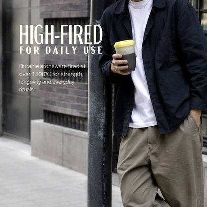 Person holding a coffee cup with text about high-fired stoneware.