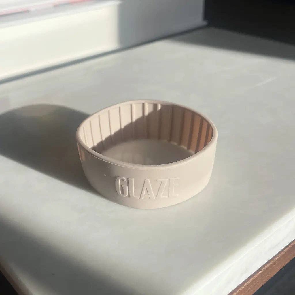 Beige coffee cup band with 'GLAZE' branding on a light surface