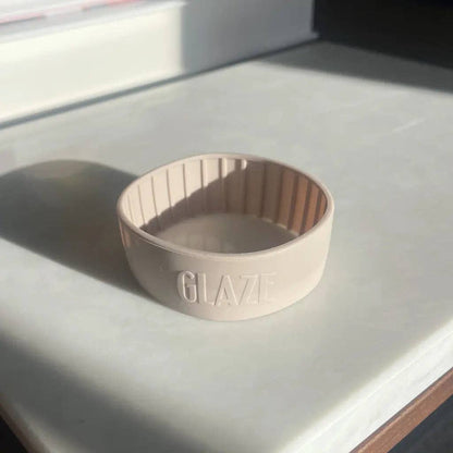 Beige coffee cup band with 'GLAZE' branding on a light surface