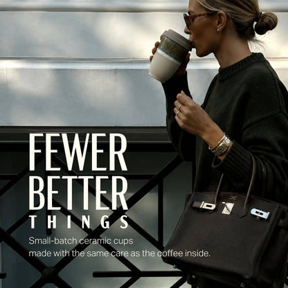 Woman drinking from a ceramic cup with text 'FEWER BETTER THINGS' and product description.