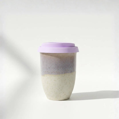 Two-toned ceramic cup with a purple lid on a white background