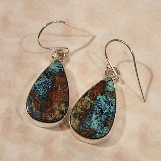 Teardrop-shaped earrings with blue and brown speckled stones on a beige background
