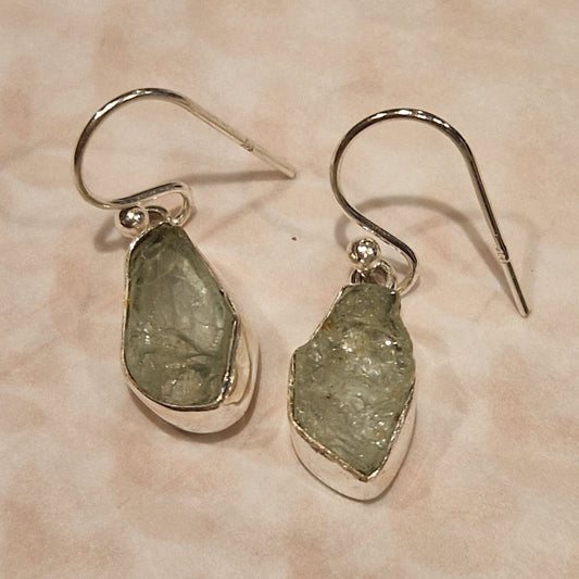 Pair of earrings with green stone drops on a beige background