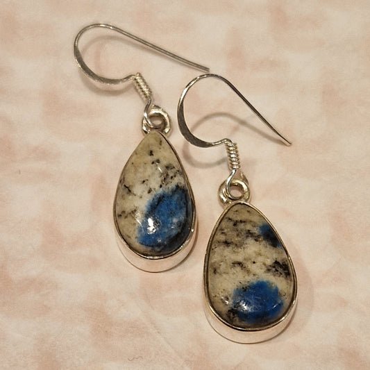 Pair of earrings with teardrop-shaped gemstones on a beige background