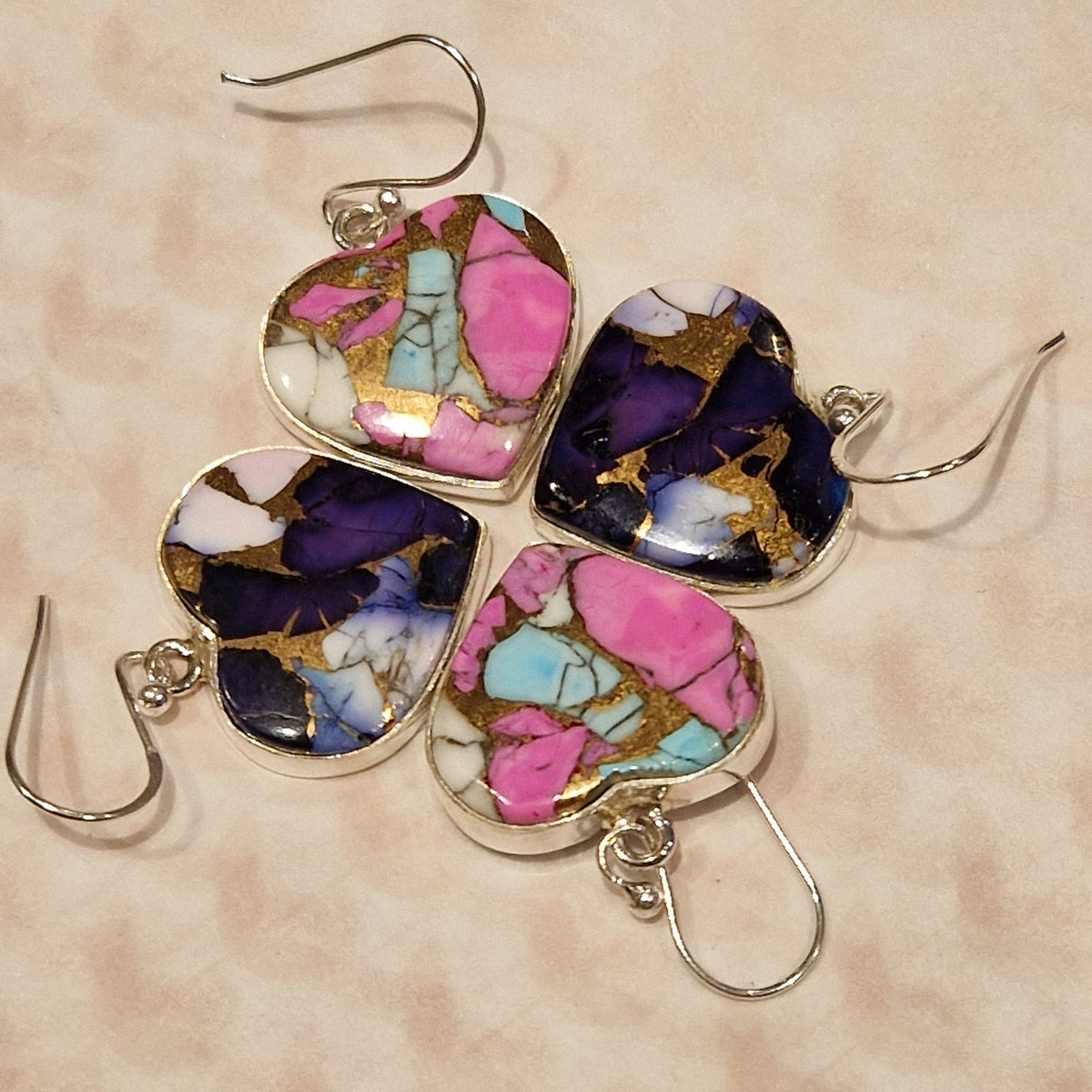 Colorful heart-shaped earrings on a beige background